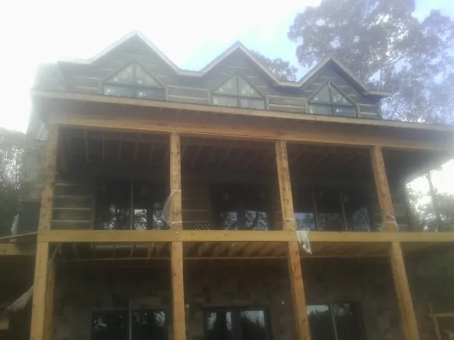 Dormers and porch framing on a large log home under construction — Roof Coating work by our crew in Monterey