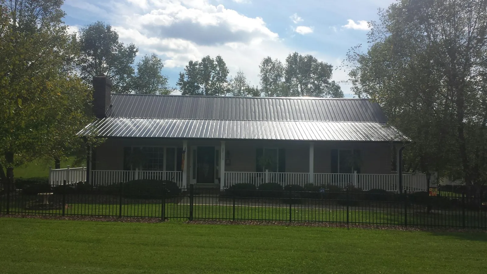 Gray metal roof on a brick ranch with a full width front porch — Gutter Guard Installation work by our crew in Monterey