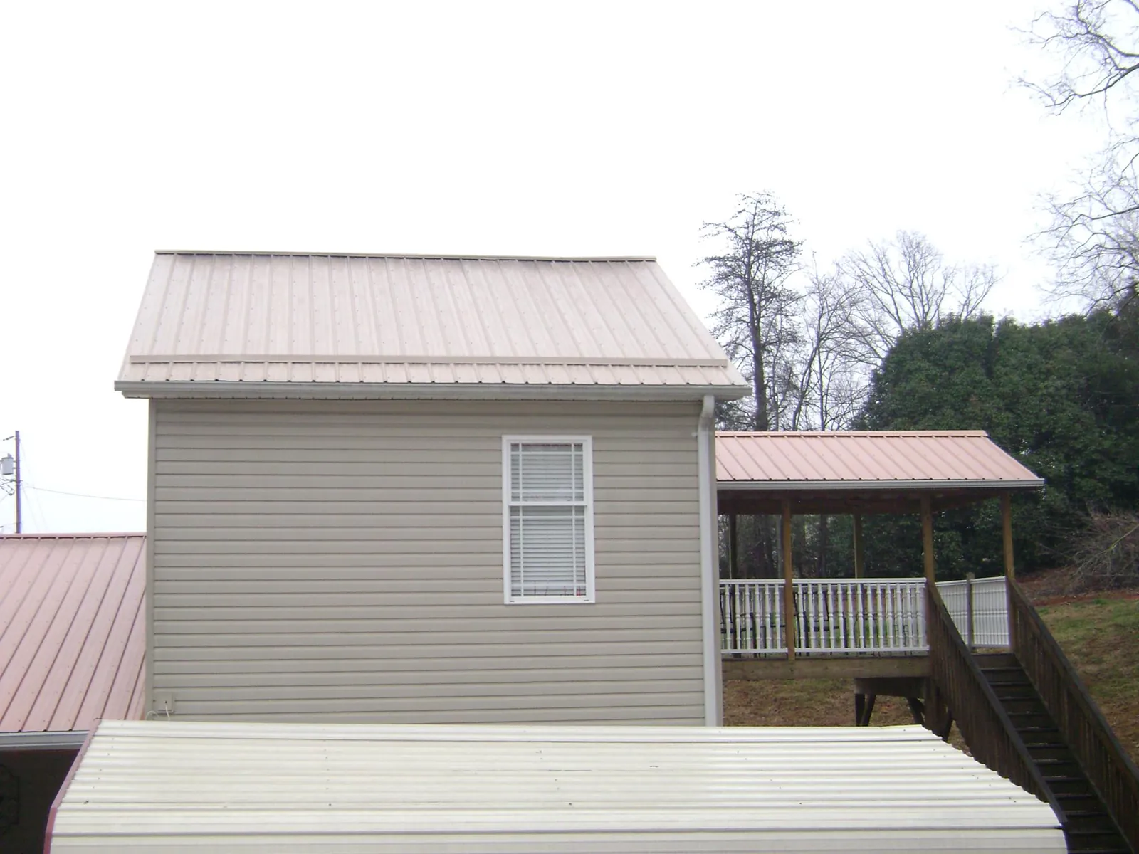 Tan metal roofs on a two story addition and attached porch in Monterey